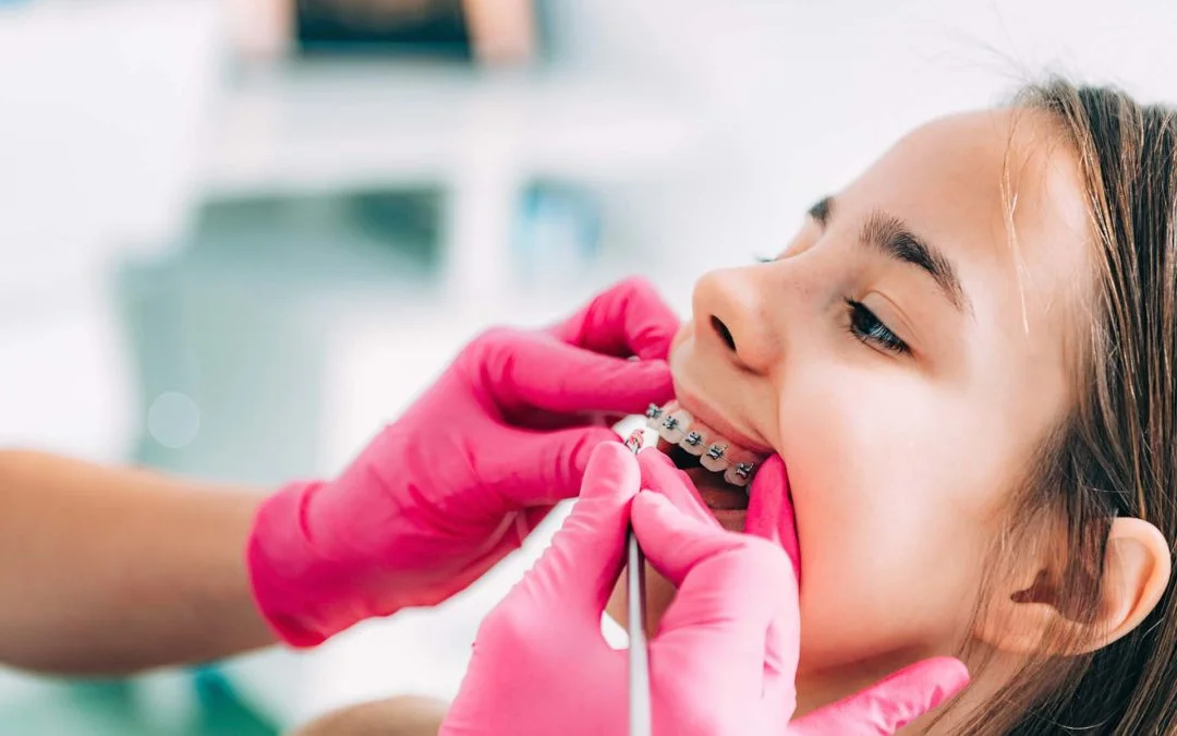 Orthodontist checking young girls braces